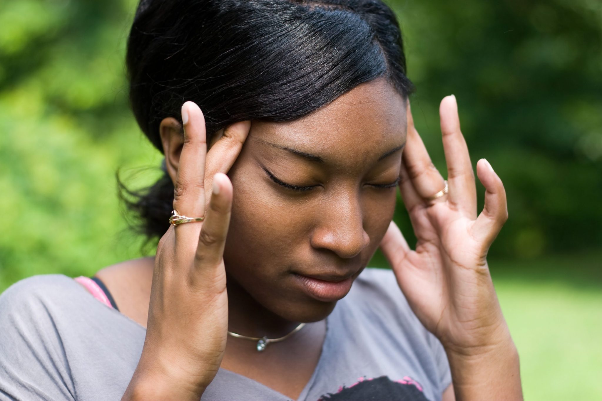 This young woman is experiencing intense stress or pain from a splitting headache.